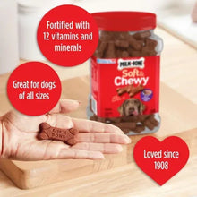 Dog treat jar with brown bone-shaped treats held in a person’s hand