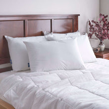 Two white cooling pillows on a bed with quilted white comforter