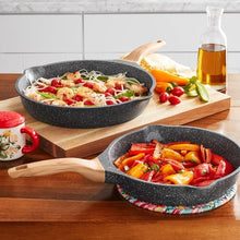Two charcoal speckle cast aluminum skillets with wooden handles, filled with cooked food