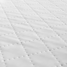 Close-up of white quilted changing pad fabric with dotted stitching