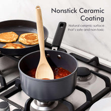Small dark gray saucepan on gas stove with wooden spoon and black handle