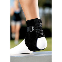 Black ankle brace worn with adjustable straps on foot outdoors