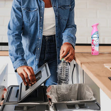 Febreze Air Mist spray bottle held near kitchen counter and trash bin