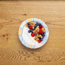 Disposable paper bowl with mixed berries and granola, blue-and-gold patterned rim