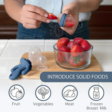 Blue octopus feeder teether with clear feeding caps beside strawberries