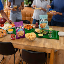 Queso dip jar on party table with tortilla chips and snack toppings