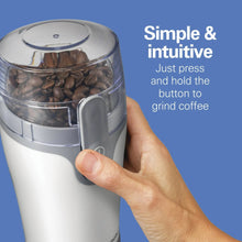 White electric coffee grinder with clear hopper, hand pressing the grind button