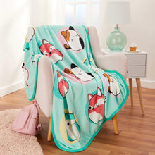 Teal kids fleece throw blanket with animal face print, folded over a chair