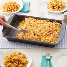 Oblong non-stick baking pan filled with baked crumbs, with serving scoop