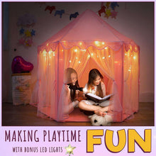 Pink princess play tent with warm LED star lights glowing and two girls reading inside.