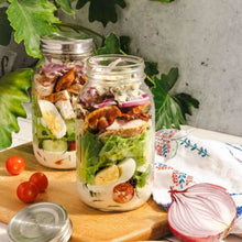 Quart glass mason jars with metal lids, filled with layered salad ingredients