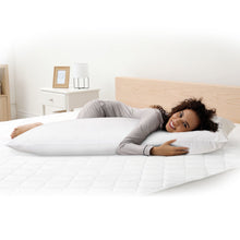 White body pillow used for side sleeping, shown with a person resting on it.