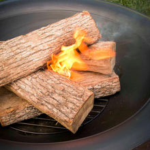 Fire starter cube burning on firewood logs in a metal fire bowl