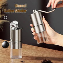 Stainless manual coffee grinder held in hand, with black top and visible grind settings