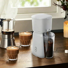 Soft silver single-serve iced coffee maker beside two small iced coffee cups
