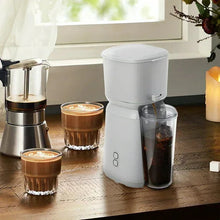 Single serve iced coffee maker with clear ice container and small glass on counter