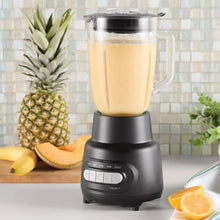 Glass jar blender with black base and jar filled with pale smoothie