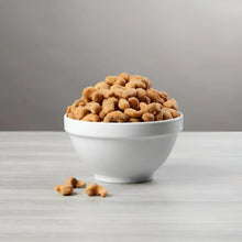 Butter toffee cashews in a white bowl with loose nuts