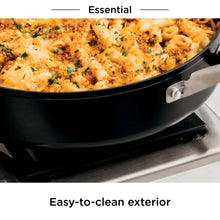 Black nonstick frying pan filled with macaroni and melted cheese, side handle visible