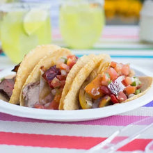 White paper dinner plate with tacos filled with diced vegetables