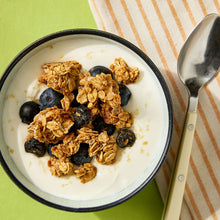 Granola in a bowl with blueberries and a spoon on striped cloth