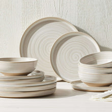 Cream dinner plates stack, showing concentric spiral ridges around the rim