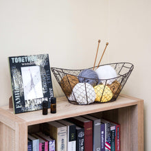 Chicken wire storage basket with handles on tabletop, holding yarn and decorative items