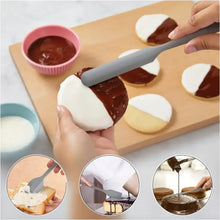 Gray silicone spatula lifting melted chocolate from a baking board
