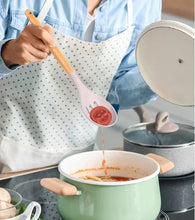 Silicone serving spoon with bamboo handle lifting tomato sauce from a pot