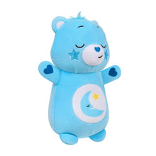 Blue plush bear toy angled view with sleepy smile, star patch, and moon emblem on front
