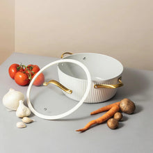 White ribbed Dutch oven with lid and gold handles on countertop