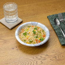 Disposable paper bowl filled with noodles and vegetables