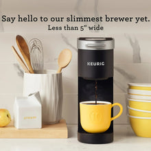 Black Keurig K-Mini single serve coffee maker next to a yellow mug