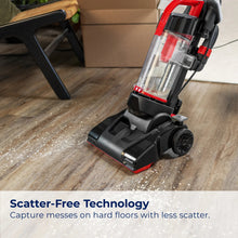 Upright vacuum with clear cyclone-style dirt bin and red base trim on hard floor.
