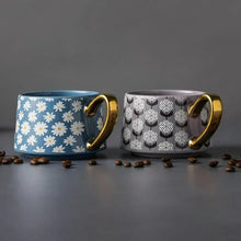 Stoneware teacup mugs, blue daisy and gray circle prints, each with gold handle