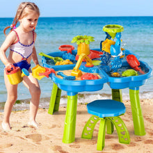 Toddler playing at outdoor sand and water table with dinosaur waterwheel and sand toys