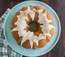 Bundt cake on plate with decorative ring cutout and white icing drizzle