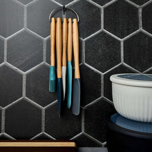 Five silicone utensils with beechwood handles hanging on a ring, blue and teal heads