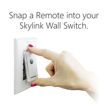 Wall light switch with snap-on remote, hand pressing the remote button.