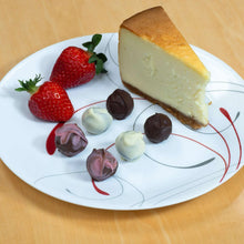 Cheesecake slice with dark and pale truffles and strawberries on a plate