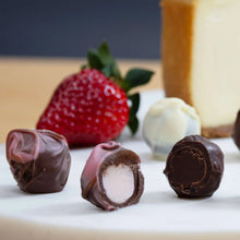 Cheesecake truffle assortment in dark and white chocolate with strawberry garnish