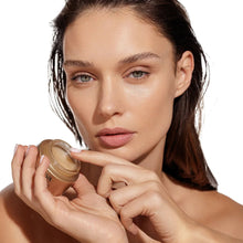 AHAVA smoothing cream jar held near face by a model