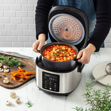 Rice cooker on counter with inner pot filled with stew; hands holding the handles