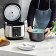Compact view of a stainless rice cooker on a countertop with an open inner pot