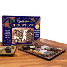 Chocolate charcuterie party tray with assorted chocolates and nuts beside gift box