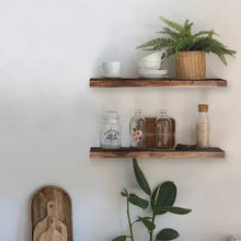 Two floating wood shelves on a white wall with decorative jars and a plant