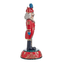 Nutcracker figurine side view, red coat with gold trim, teal boots, blue hat, red base.