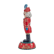 Nutcracker figurine side view, red uniform with gold details, blue hat and white beard, red base.