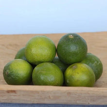 Fresh limes with green rinds stacked on a wooden surface