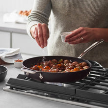 Black nonstick skillet with food, utensil resting on rim